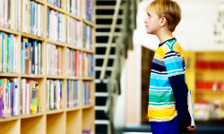 young reader looks at a bookshelf